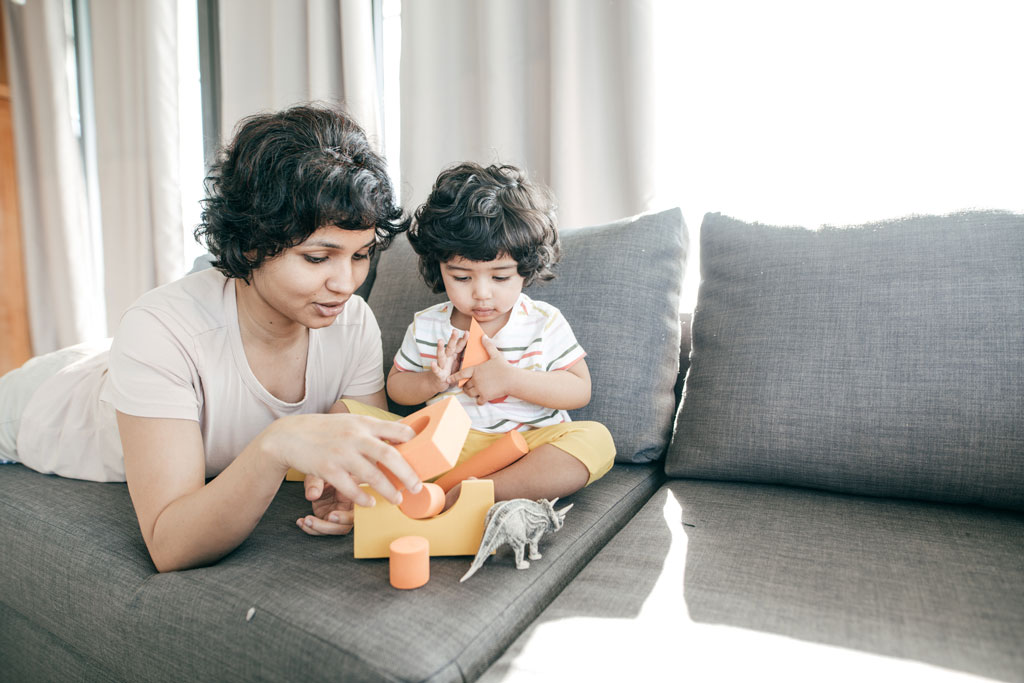 a mother and her small daughter playing with blocks on the couch