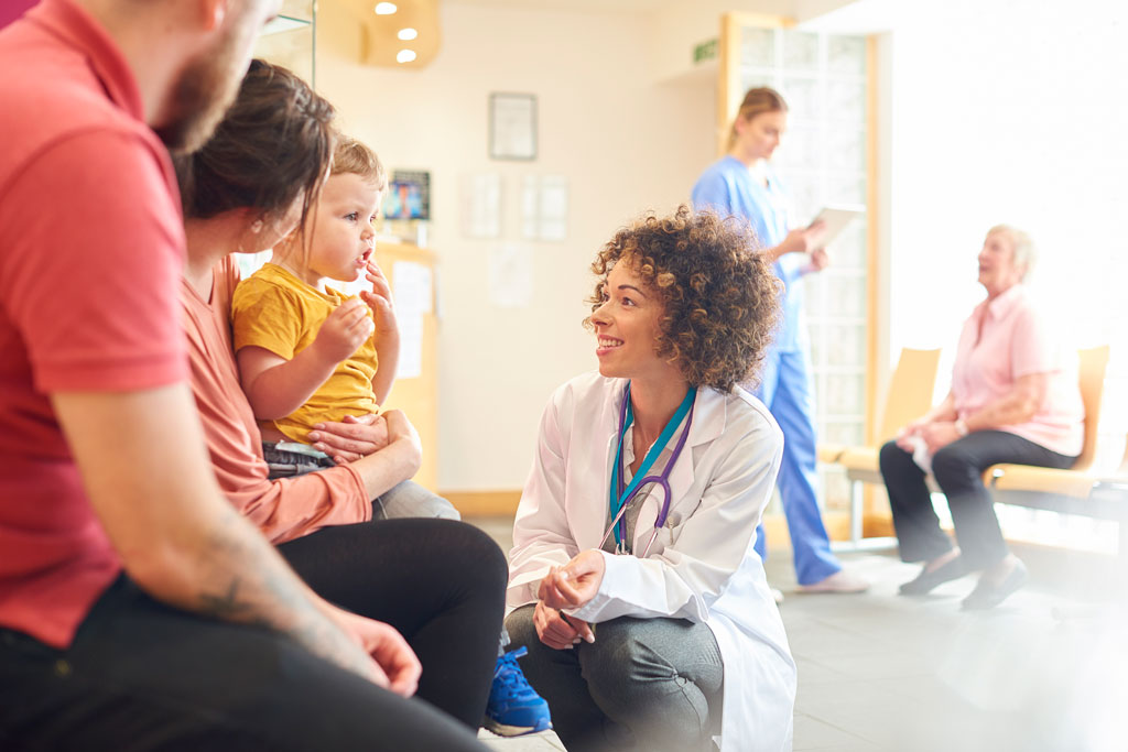 a doctor consulting with a young child sitting on his mother's lap