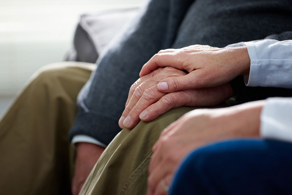 a senior couple sitting holding hands
