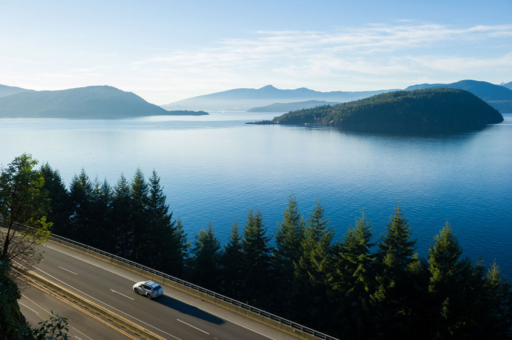 a lone vehicle traveling the sea to sky highway with the Sunshine Coast in the distance