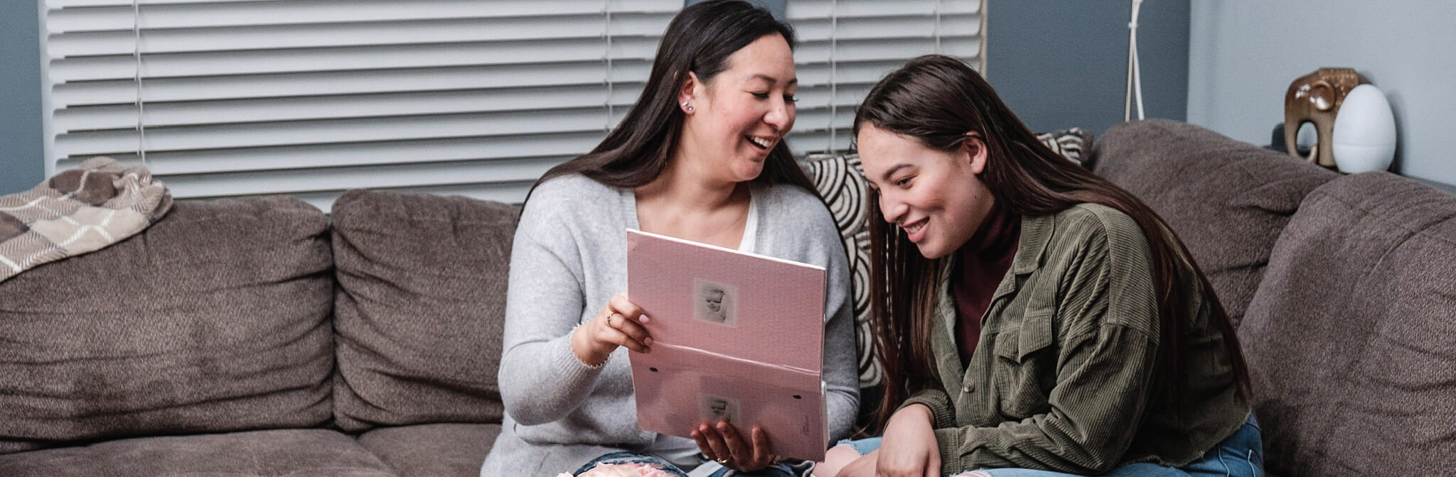 two young adult ladies looking at babies pictures and laughing