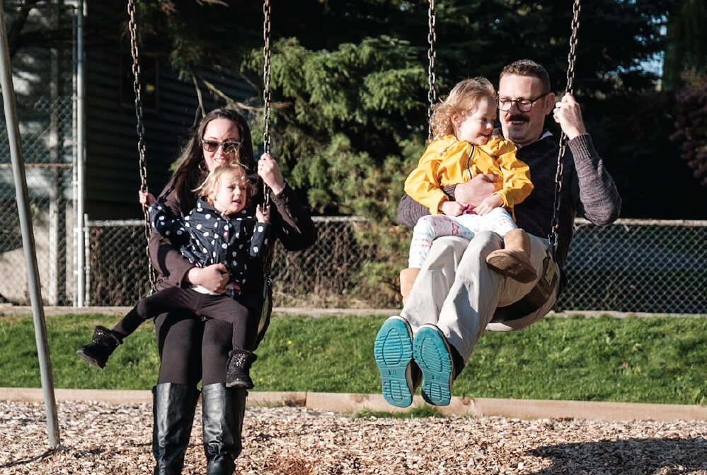 a family with two children playing with a swing outside