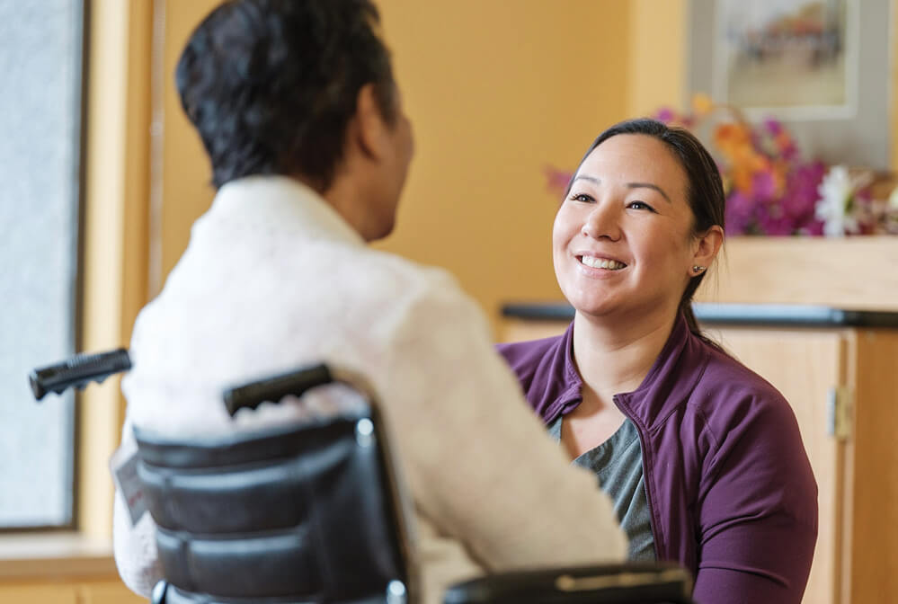 a man seated in a wheelchair chatting with a woman