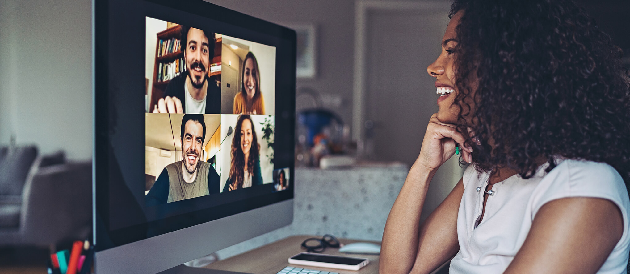 woman smiling at a group of coworkers on video chat